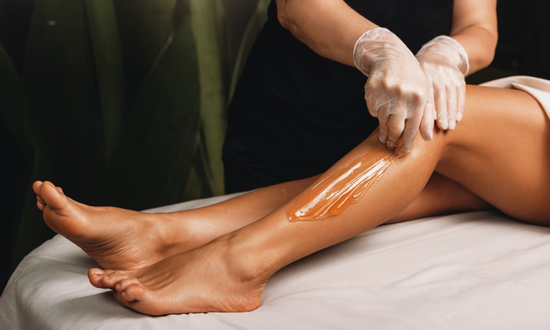 woman sugaring legs technician
